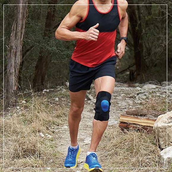 Man with knee brace running through woods