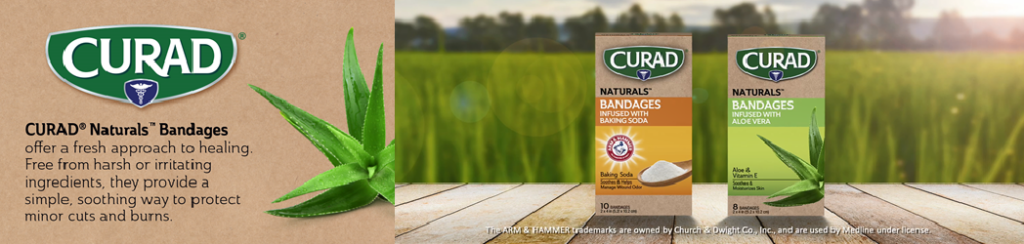 A promotional image for CURAD Naturals Bandages featuring two products. On the left, a fresh aloe plant and the bandage box with 'infused with Baking Soda' label. On the right, a bandage box labeled 'infused with Aloe Vera' is placed on a wooden surface with a lush green field in the background. Text highlights that the bandages are a 'fresh approach to healing, free from harsh ingredients.